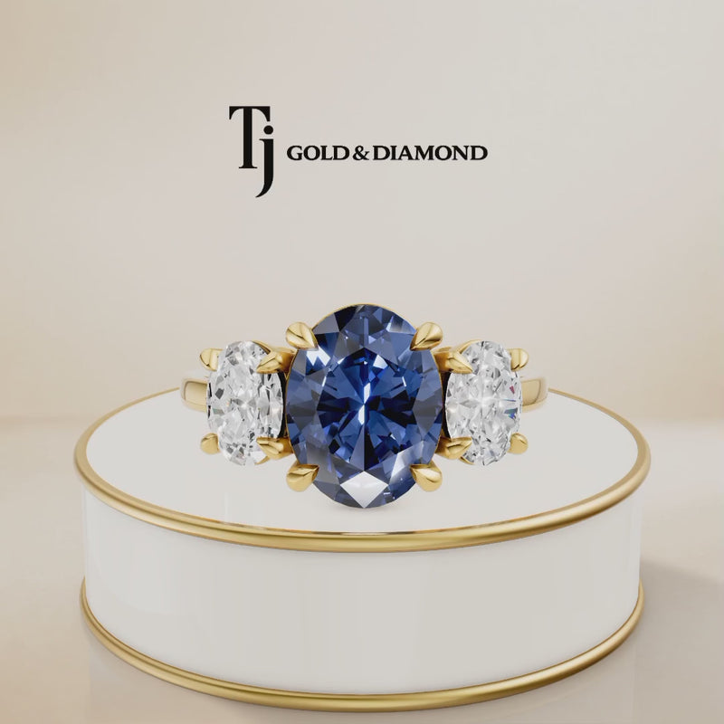360° product view of an Oval Cut Lab-Created Blue Sapphire & Lab-Grown Diamond Trilogy Ring in 18kt yellow gold featuring an oval royal blue sapphire with oval lab-grown diamond side stones.