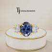 360° product view of an Oval Cut Lab-Created Blue Sapphire & Lab-Grown Diamond Trilogy Ring in 18kt yellow gold featuring an oval royal blue sapphire with oval lab-grown diamond side stones.