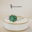 360° product view of a round cut lab-created emerald trilogy engagement ring in 18kt yellow gold with round brilliant lab-grown diamond side stones and a classic four claw basket setting.